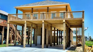 Une maison à deux étages avec une terrasse en bois et un balcon couvert.