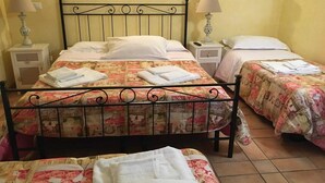 A room with three beds, each with floral bedding and white towels. There are bedside tables with lamps and a wall-mounted light fixture. - Apartment on a family house (Roma)