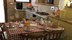 A cozy kitchen with a dining table set for four, featuring a red and white checkered tablecloth and wooden chairs. - Apartment on a family house (Roma)