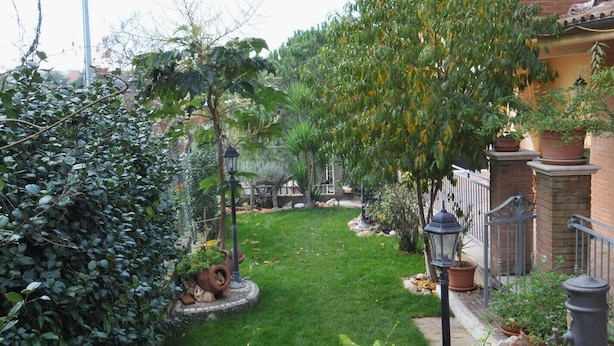 A well-maintained garden with a lawn, various plants, and a brick wall. - Apartment on a family house (Roma)