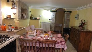 A cozy kitchen with a dining table set for four, featuring a checkered tablecloth and wooden chairs. - Apartment on a family house (Roma)