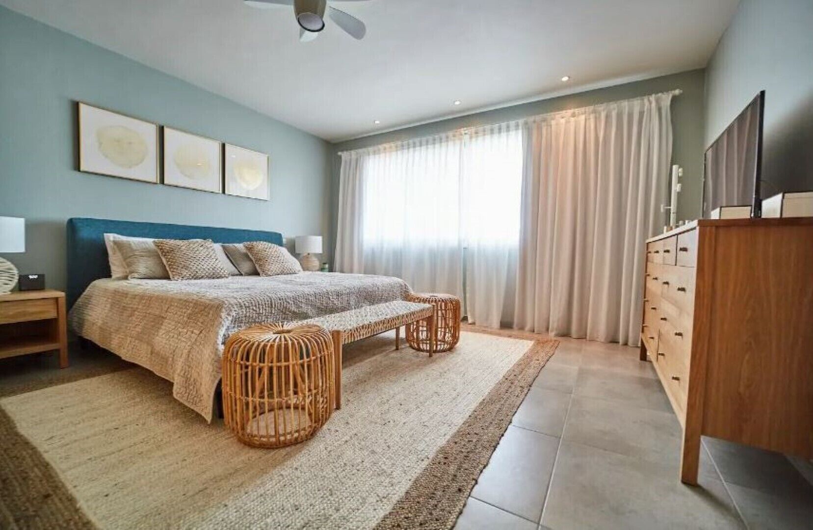 A bedroom with a bed, bedside tables, a wardrobe, and a large window with curtains.