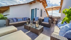 An outdoor seating area with wicker furniture, a glass-top coffee table, and a view of the sky. - New loft duplex with rooftop deck (Dominicus)