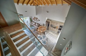 Um interior espaçoso com teto alto, área de jantar com mesa redonda e cozinha com armários de madeira.