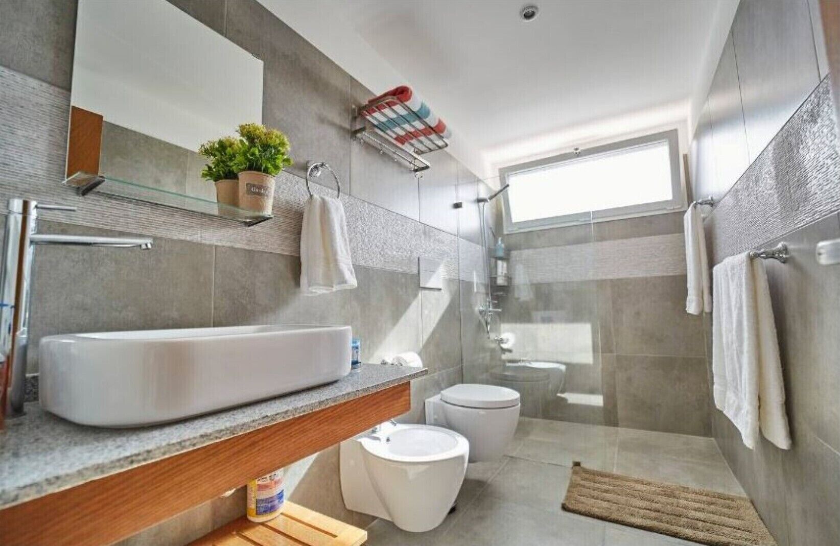 A modern bathroom with a large sink, toilet, and shower.