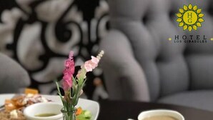 Una mesa de comedor con una taza de café, un plato de comida y un jarrón con flores.
