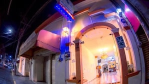 Una entrada de hotel con piso de baldosas, un mostrador de recepción y un candelabro.