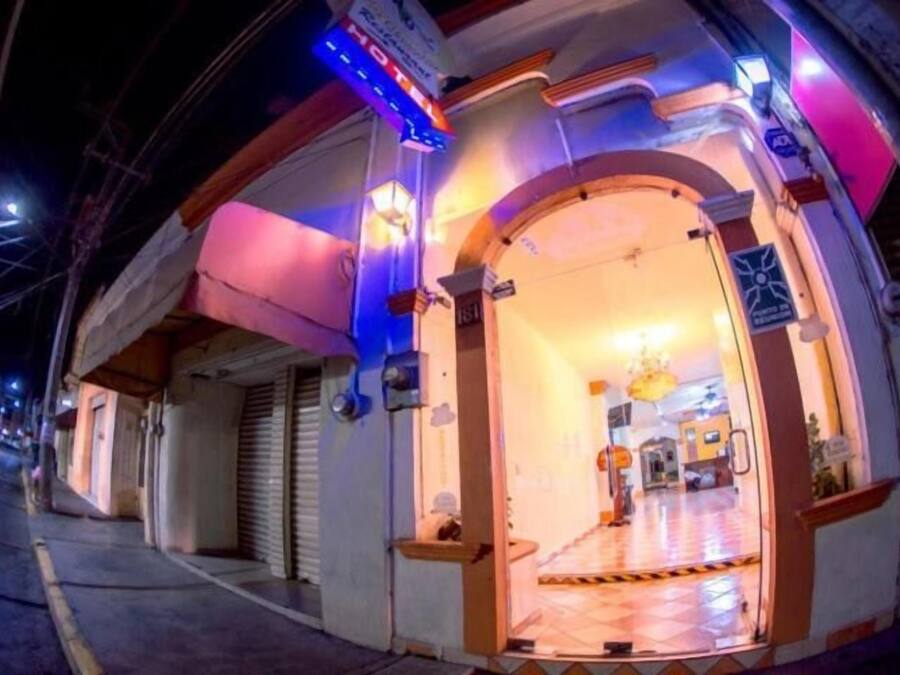 Una entrada de hotel con piso de baldosas, un mostrador de recepción y un candelabro.