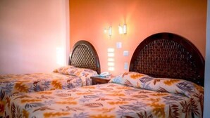 Una habitación con dos camas, cada una con cubrecama estampado de flores, y una lámpara fijada a la pared.