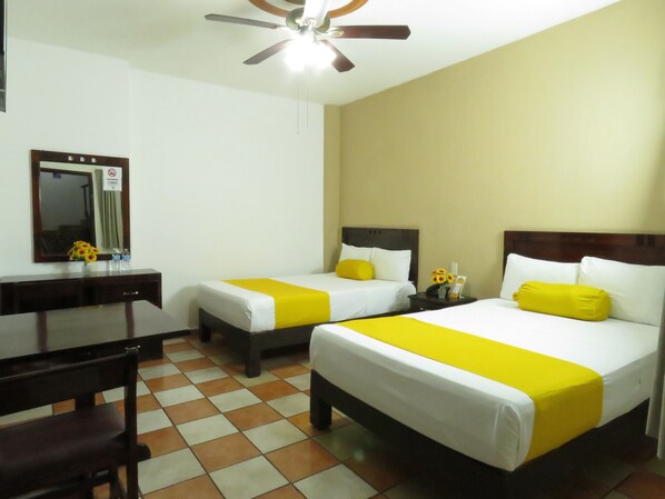 A hotel room with two beds, a desk, and a chair. - Hotel Los Girasoles (Tepic)