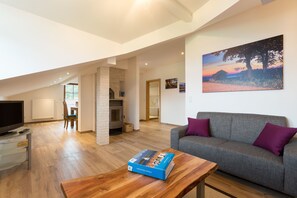 Un vaste espace de vie comprenant un canapé, une table basse en bois et un téléviseur posé sur un meuble.