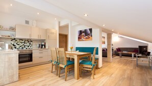 Una cocina moderna con armarios de madera, un comedor con mesa y sillas, y una sala de estar con sofá y una mesita de centro.