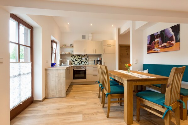 Une cuisine moderne avec un coin repas, un plancher en bois et une grande fenêtre.