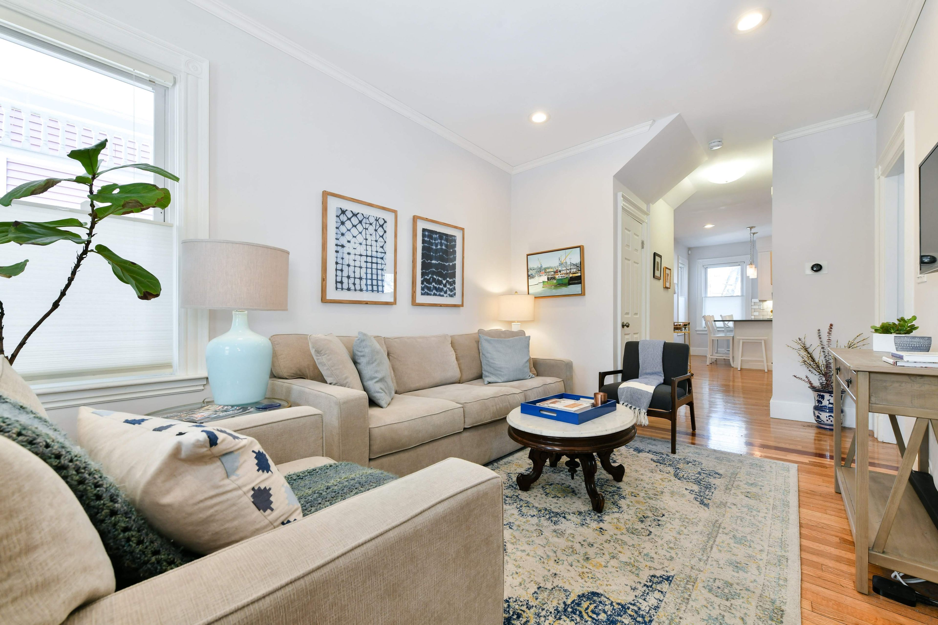 A modern living room with a sofa, coffee table, and artwork on the walls.