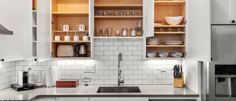 Una cocina moderna con armarios blancos, un lavamanos de acero inoxidable y un horno empotrado.