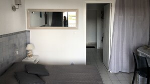 Een slaapkamer met een bed, een nachtkastje, een lamp, een spiegel en een badkamer die door een open deur zichtbaar is.