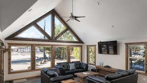 A spacious living room with a high ceiling, large windows, and a modern fireplace. - Summit View Cabin Rental (British Columbia)