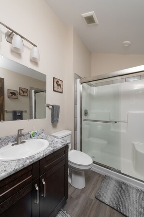 Une salle de bain moderne avec un lavabo en marbre, des toilettes et une douche à parois de verre.