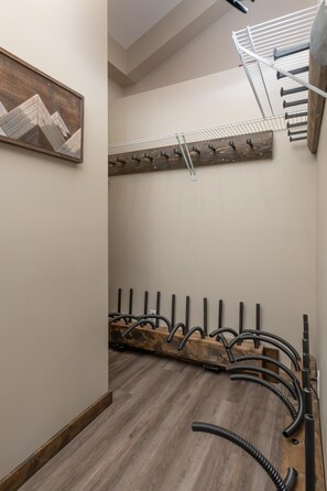 Un couloir avec un plancher en bois, un porte-manteau et un ventilateur de plafond.