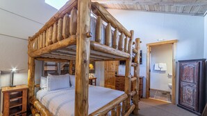 Una cama con dosel de madera rústica en una habitación con un armario de madera, un escritorio y una puerta.