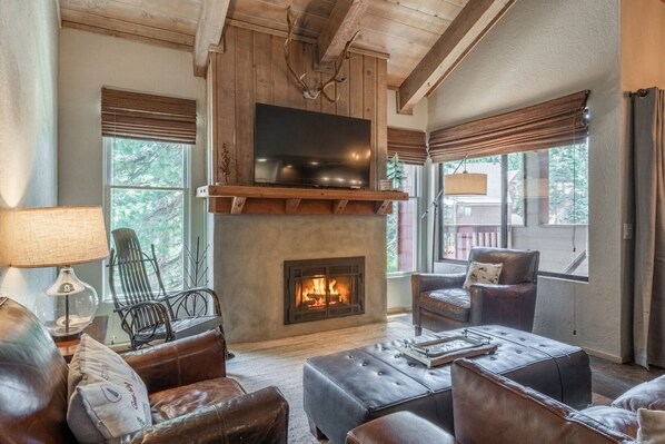 A cozy living room with a fireplace, leather furniture, and a television mounted above it. - Ski-Back Condo Near Village & Gondola 420 (Mammoth Lakes)