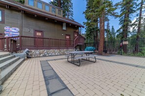 A building with a stone wall, a picnic table, and a metal railing. - Ski-Back Condo Near Village & Gondola 420 (Mammoth Lakes)