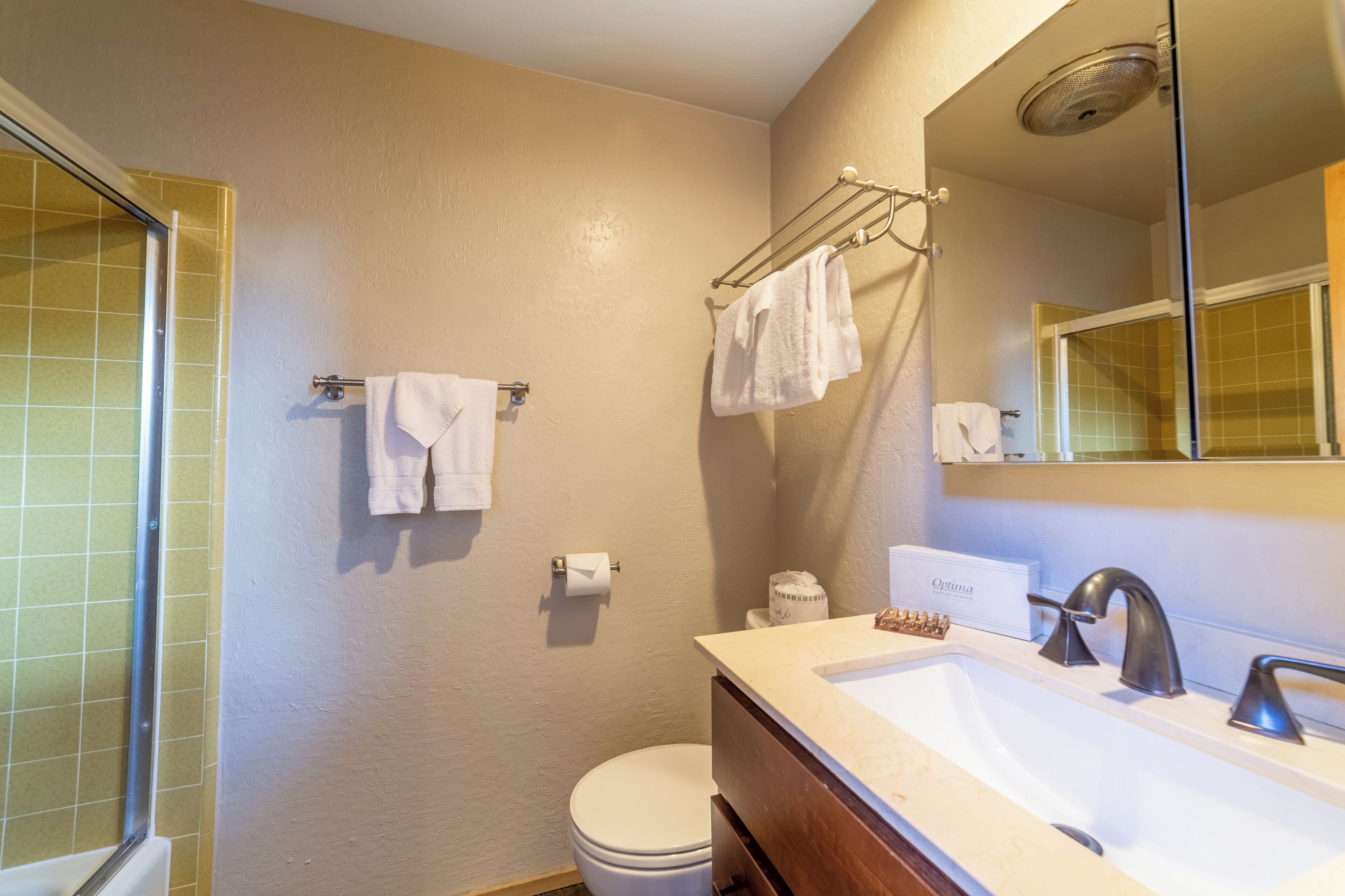 A bathroom with a shower, toilet, sink, and towel rack.