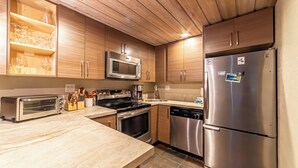 Una cocina moderna con armarios de madera, electrodomésticos de acero inoxidable y encimera de mármol.
