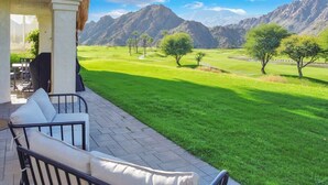 A patio with outdoor furniture overlooking a well-maintained lawn and mountains. - Golfer's Paradise | 3BR Santa Rosa Cove (La Quinta)