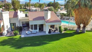A residential property with a swimming pool, patio furniture, and a well-maintained lawn. - Golfer's Paradise | 3BR Santa Rosa Cove (La Quinta)
