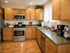 A modern kitchen with wooden cabinets, stainless steel appliances, and a granite countertop. - Spacious - Three king rooms, two living rooms in a  quiet neighborhood (Alamosa)