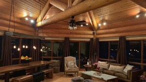Ein gemütliches Blockhaus-Interieur mit einem Holzesstisch, Bänken, einer Couch und Poufs.