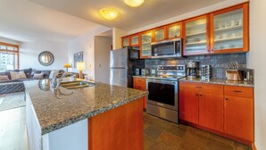 Eine moderne Küche mit Granit Arbeitsplatten, Edelstahlgeräten und Holzschränken.