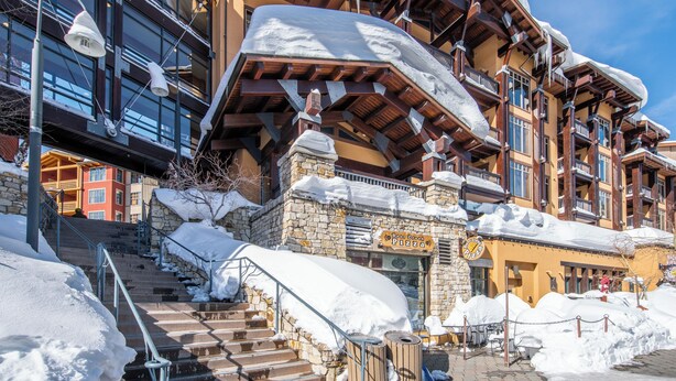 Ein mehrstöckiges Hotel mit einer steinernen Fassade, hölzernen Balkonen und einer Treppe, die zum Eingang führt.