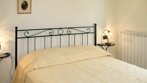 A bedroom with a bed, a nightstand, a wall-mounted lamp, and a radiator. - Lovely apartment in villa for 6 people with WIFI, pool, TV, patio and pets allowed (Pescia)