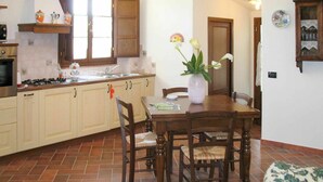 A kitchen with wooden cabinets, a stove, and a dining area with a table and chairs.
