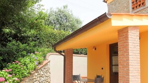A covered patio area with a stone wall and potted plants.