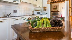 Cozinha com armários brancos, micro-ondas e cesta de vegetais no balcão.