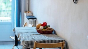 A kitchen with a wall-mounted pot rack holding various cookware. A checkered table with a basket of fruit is in the foreground. - Bright Airy Spacious Property (Passy)