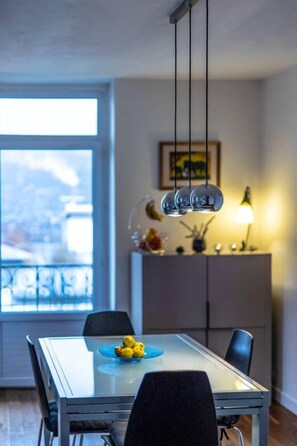 A modern dining area with a glass table, black chairs, and a blue plate of lemons.