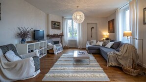 A modern living room with a fireplace, a television, and a large window. - Bright Airy Spacious Property (Passy)
