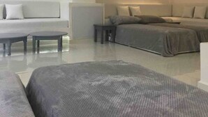 Un dormitorio moderno y luminoso con cama, sofá y una mesita.
