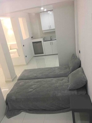 A compact room with a bed, a small table, and a kitchenette area. - - Imi White House - (Imi Ouaddar)