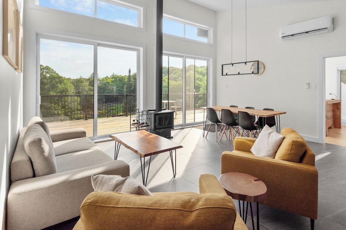 A spacious living area with a large window, a fireplace, and a dining set.