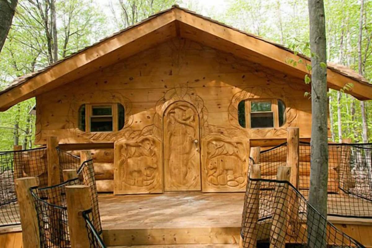 Una cabaña de madera con techo inclinado, dos ventanas y una puerta central con intrincados grabados.