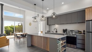 A modern kitchen with a central island, stainless steel appliances, and pendant lighting. - Parc Omega (Notre-Dame-de-Bonsecours)