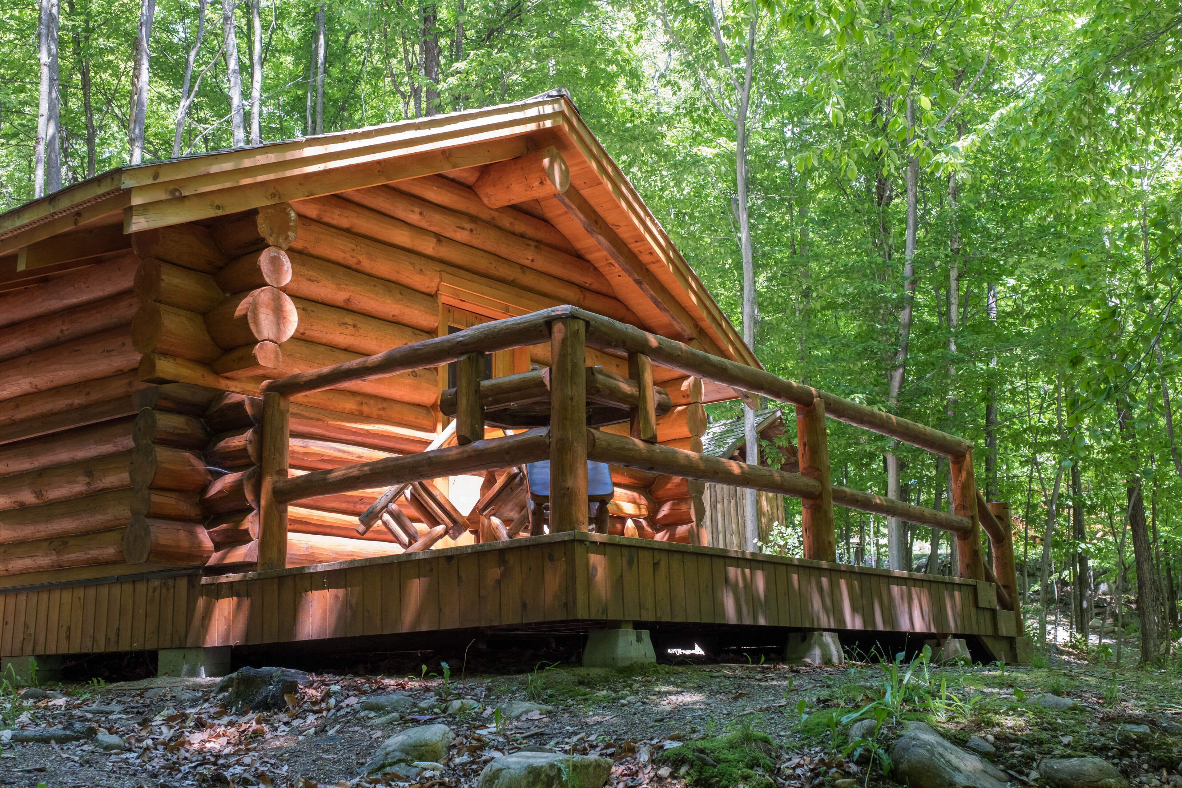 Une cabane en rondins dotée d’une terrasse en bois et d’une rambarde en métal.
