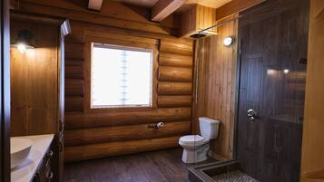 Ein Badezimmer einer Holzhütte mit Toilette, Waschbecken und Dusche.