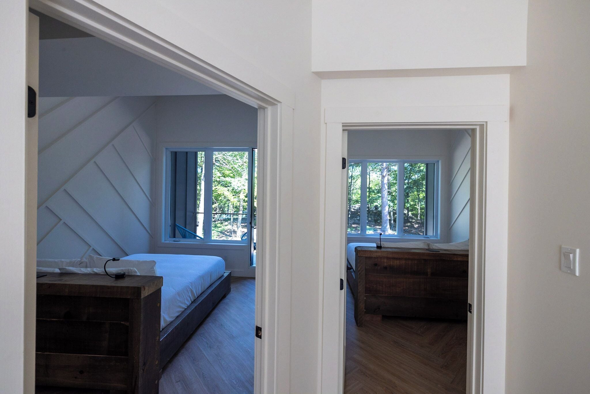 Un dormitorio con cama, cómoda de madera y ventana con vistas a  árboles.