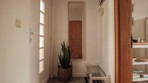 A hallway with a wooden door, a wicker basket with a plant, and a bench. - Vacation apartment CramerTwo rooms for 4 persons (Gerolzhofen)
